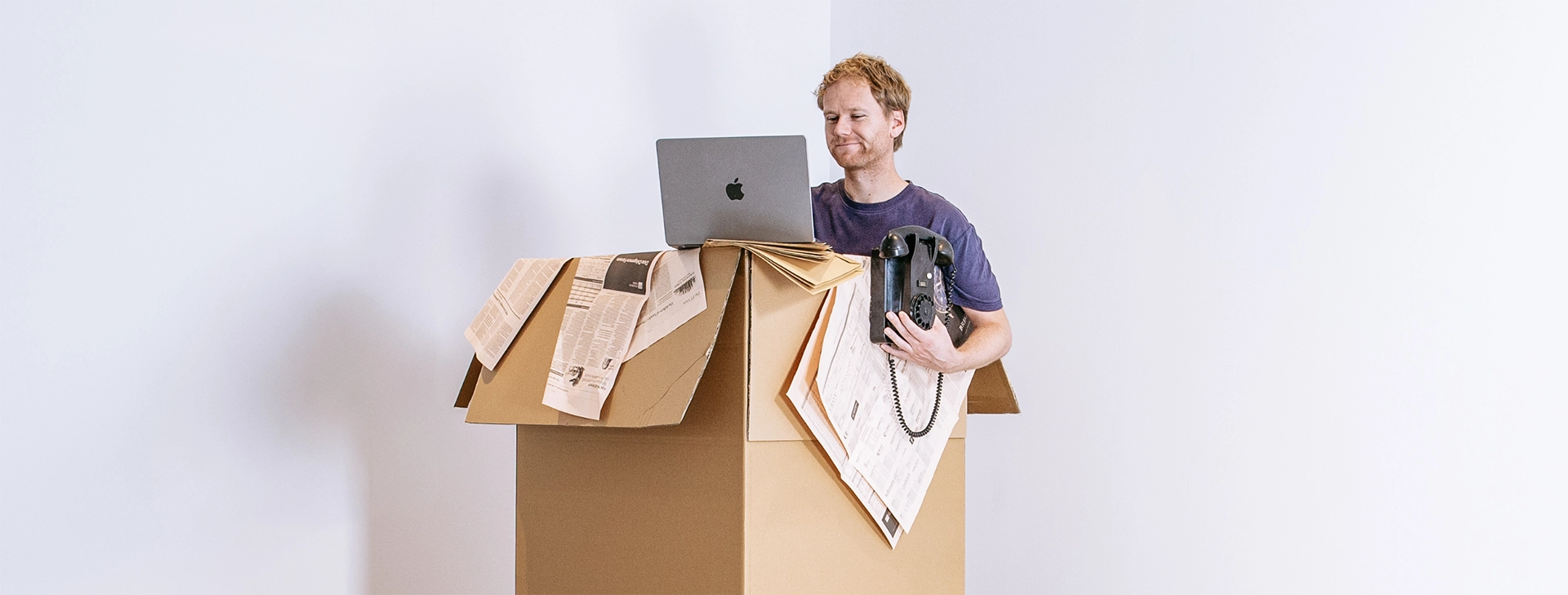 Projectmanager Lennart in doos met telefoon en laptop